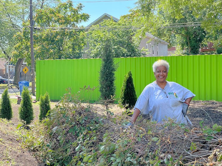 Older woman in blue t-shirt working and posing in garden in Woodlawn.