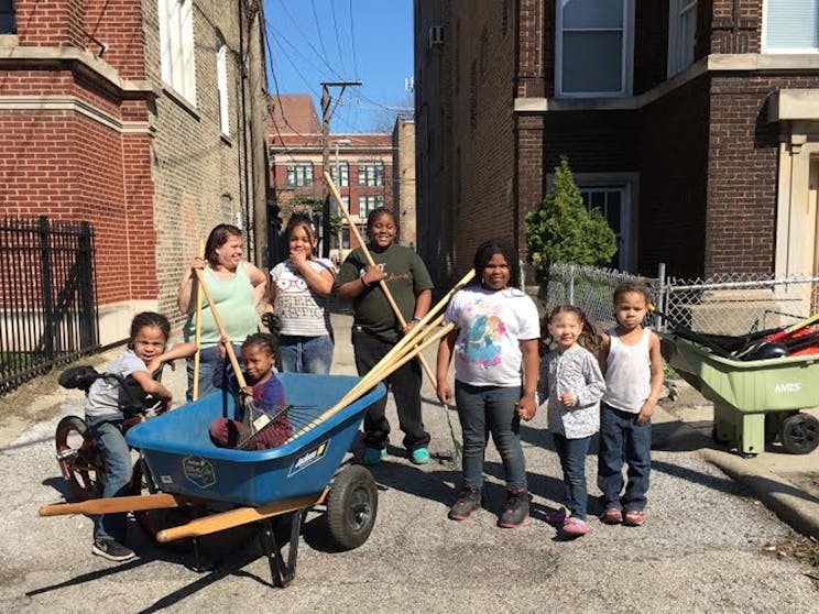 Children in Woodlawn holding yard tools to cleanup the neighborhood.
